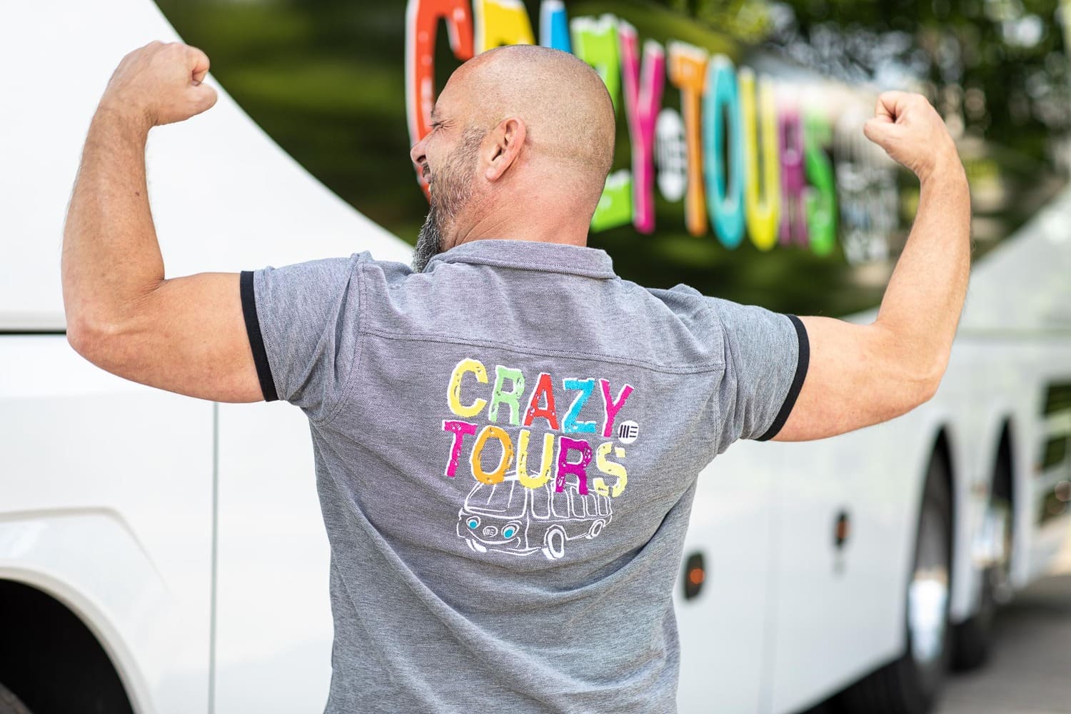 Mann steht mit dem Rücken zur Kamera und zeigt sein T-Shirt mit der Aufschrift: Crazy Tours 