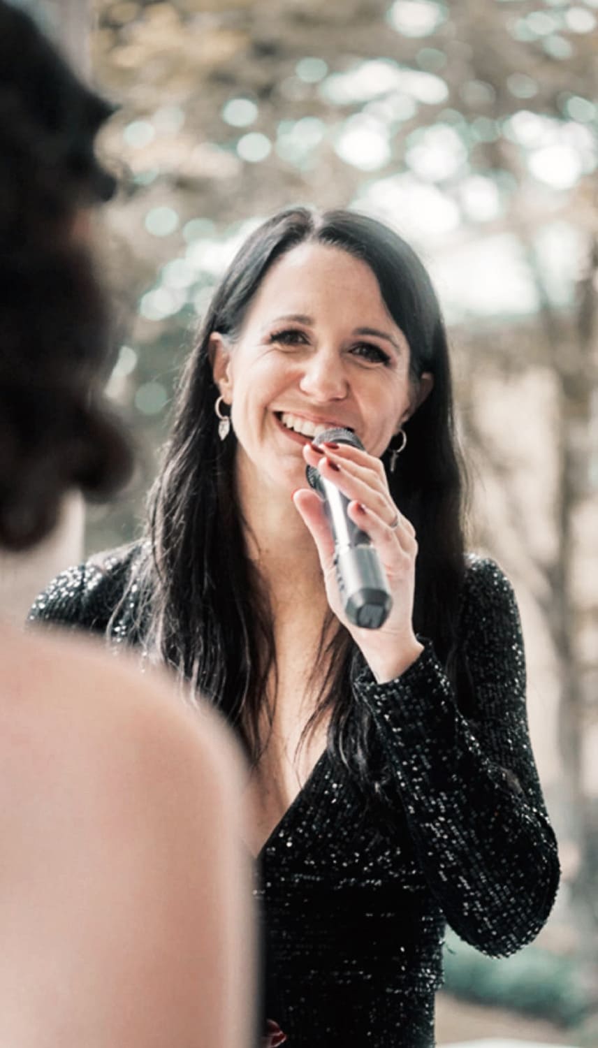 Lena lächelt und singt während sie ein Mikrofon in einer Hand hält 