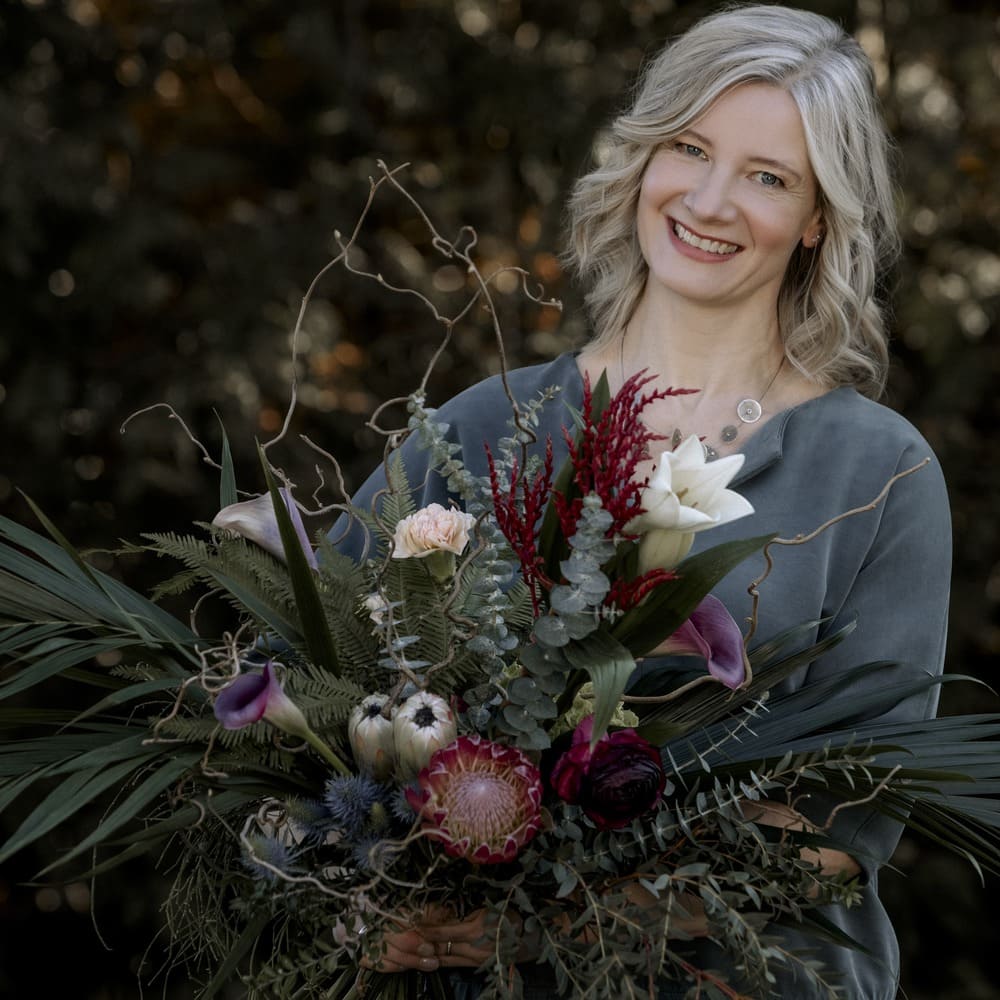Stephanie von Blumen Kuhn Floraldesign lächelt in die Kamera mit einem Blumenstrauß in der Hand